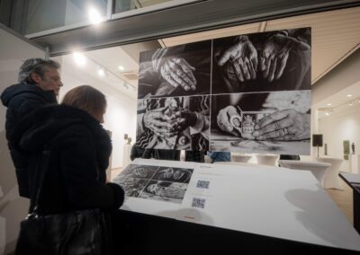 Фотографија са отварања светски значајне инклузивне изложбе „Невидљиви свет“ (World Unseen) компаније Canon у Галерији НКЈ. Приказани су посетиоци и званице у обиласку серије радова светских фотографа израђених у рељефној штампи. Кадар обухвата тактилне фотографије које слепи и слабовиди посетиоци доживљавају додиром, пропратне описе на Брајевом писму, као и посебне наочаре које посетиоцима симулирају различита оштећења вида ради подизања емпатије и свести о приступачности.